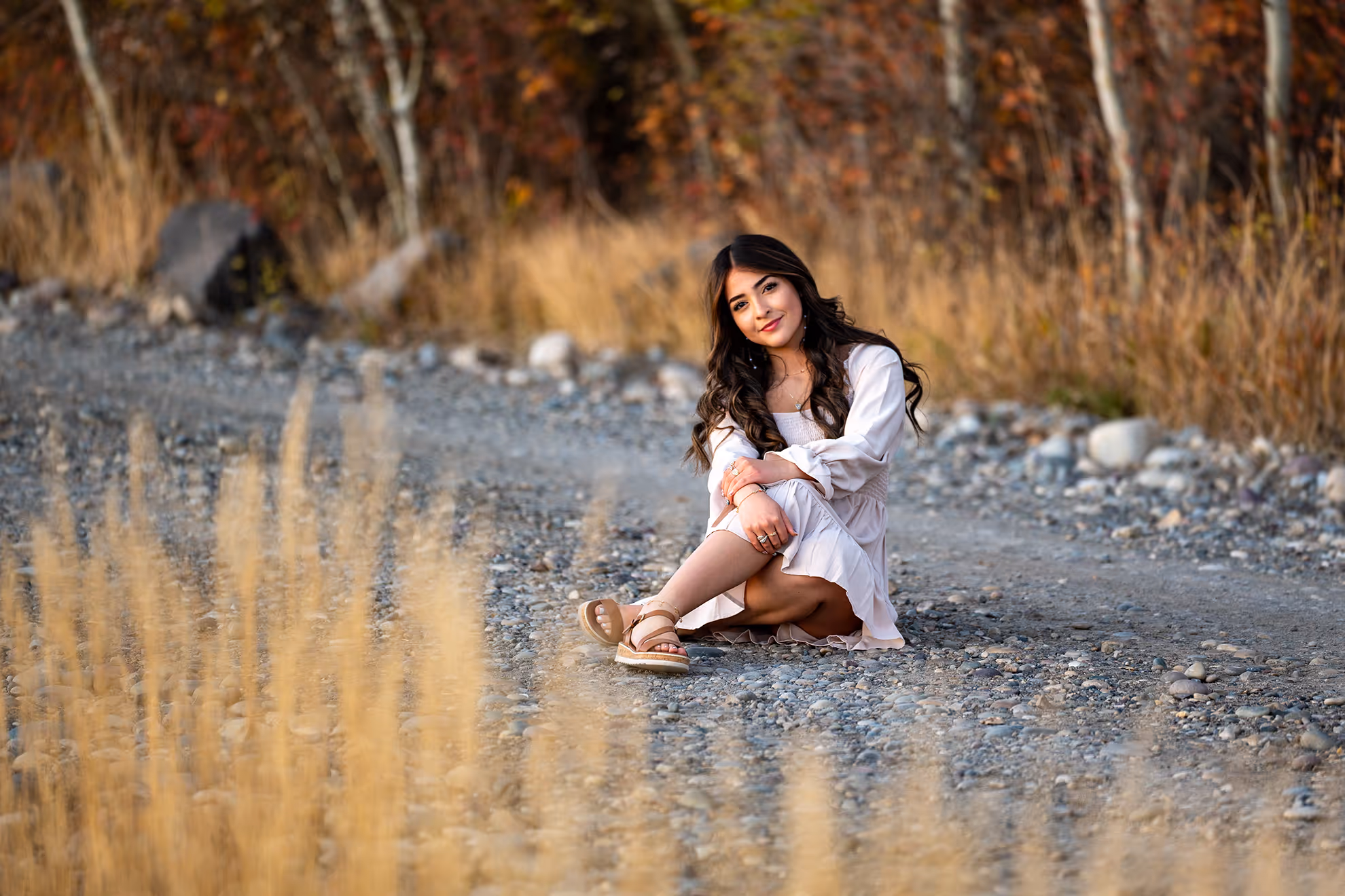 A girl sitting on the road for senior photos.