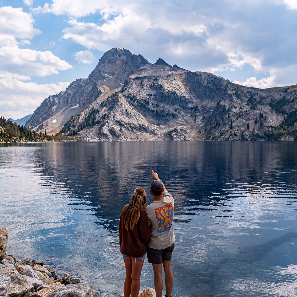 A couple pointing at a mountain across Sawtooth Lake.