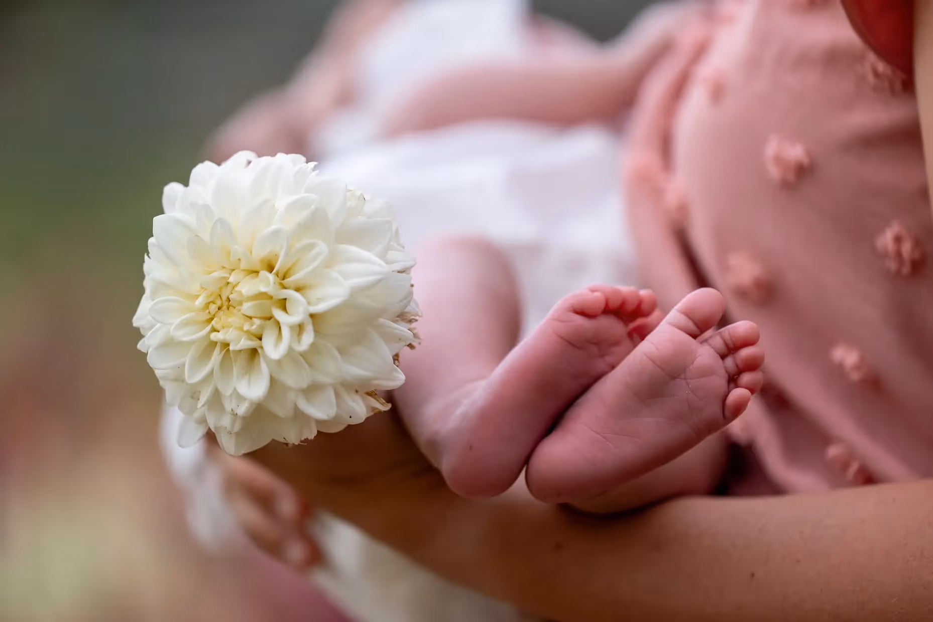 A mother holding a newborn with flowers.