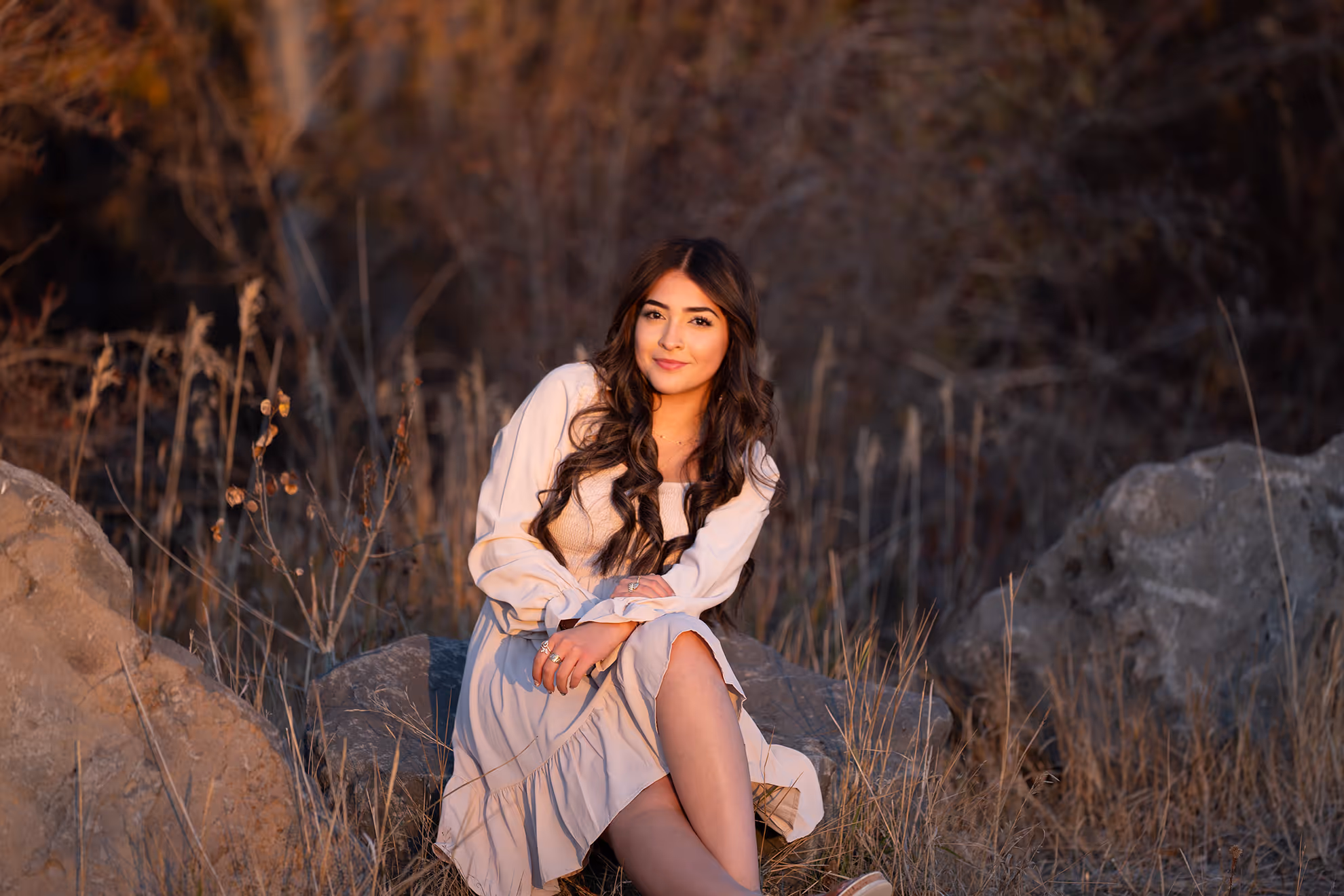 A high school senior sitting on a rock during golden hour