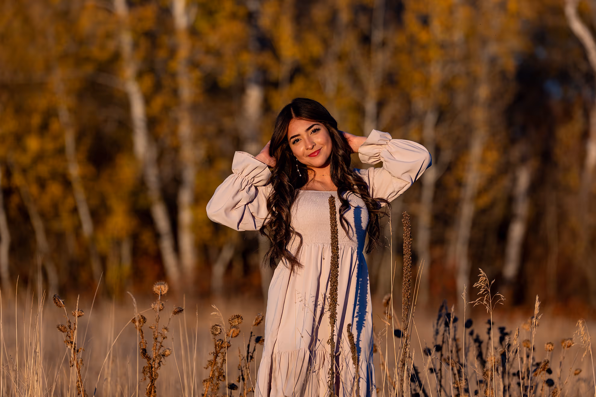 A high school senior grabbing her hair in the middle of a field.