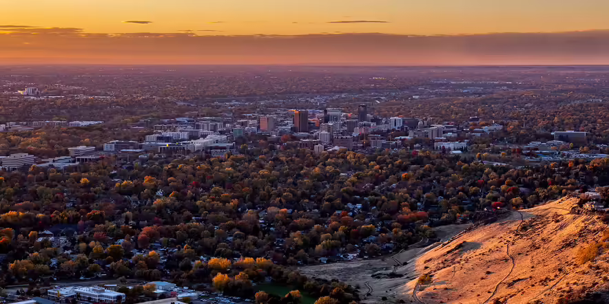 Boise, Idaho skyline at sunset viewed from Table Rock — panoramic cityscape with warm sunset sky.