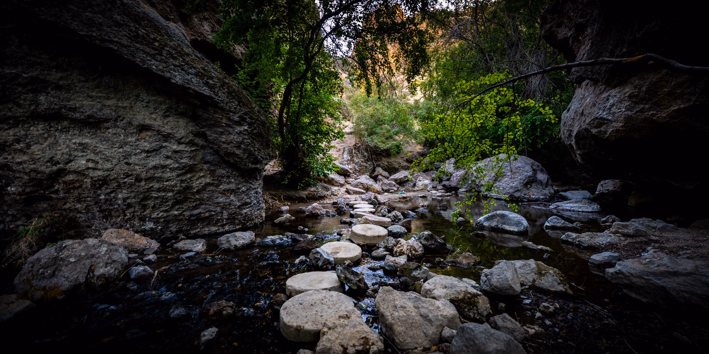 Stone steps descending toward Jump Creek Falls waterfall in Idaho, framed by rocky canyon walls and lush green vegetation