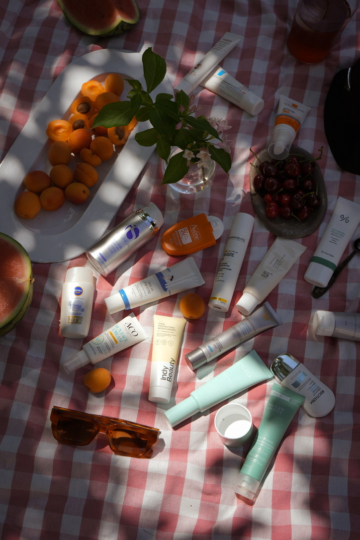 Picknick där olika solskyddsprodukter med högt UVA-skydd och frukter syns på en rutig filt, SPF från Aco, SPF från Biotherm, SPF från Nivea