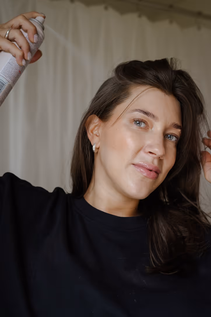 Bilden föreställer Lina Livian som visar hur torrschampo ska appliceras, man sprayar på ungefär 20 cm avstånd