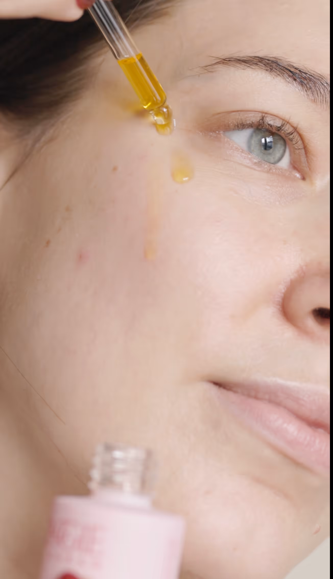 Närbild på pipett som droppar C-vitaminserum på en kind för att visa hur man använder ett serum med C-vitamin, på rengjord hud