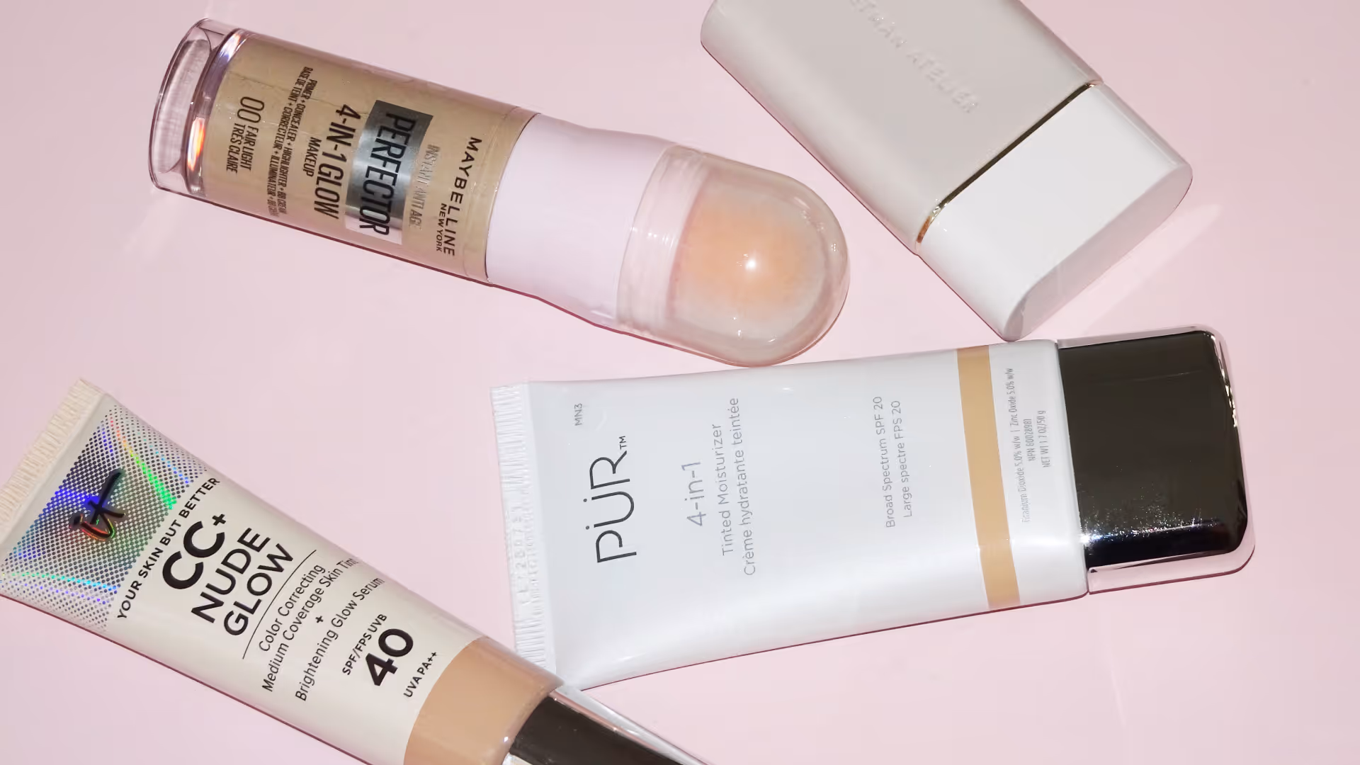 Fyra olika sminkprodukter på rosa bakgrund, inklusive CC-cream, skintints och tinted moisturizer.