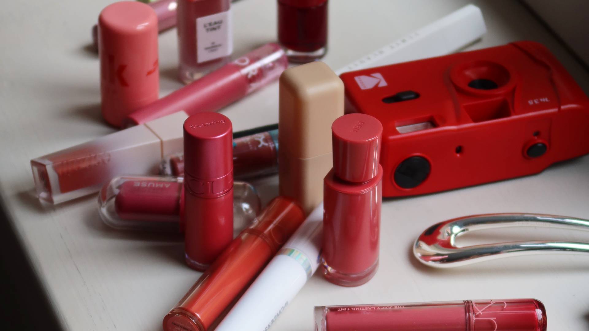 Flera olika lip tints i olika färger och förpackningar utspridda på ett bord.