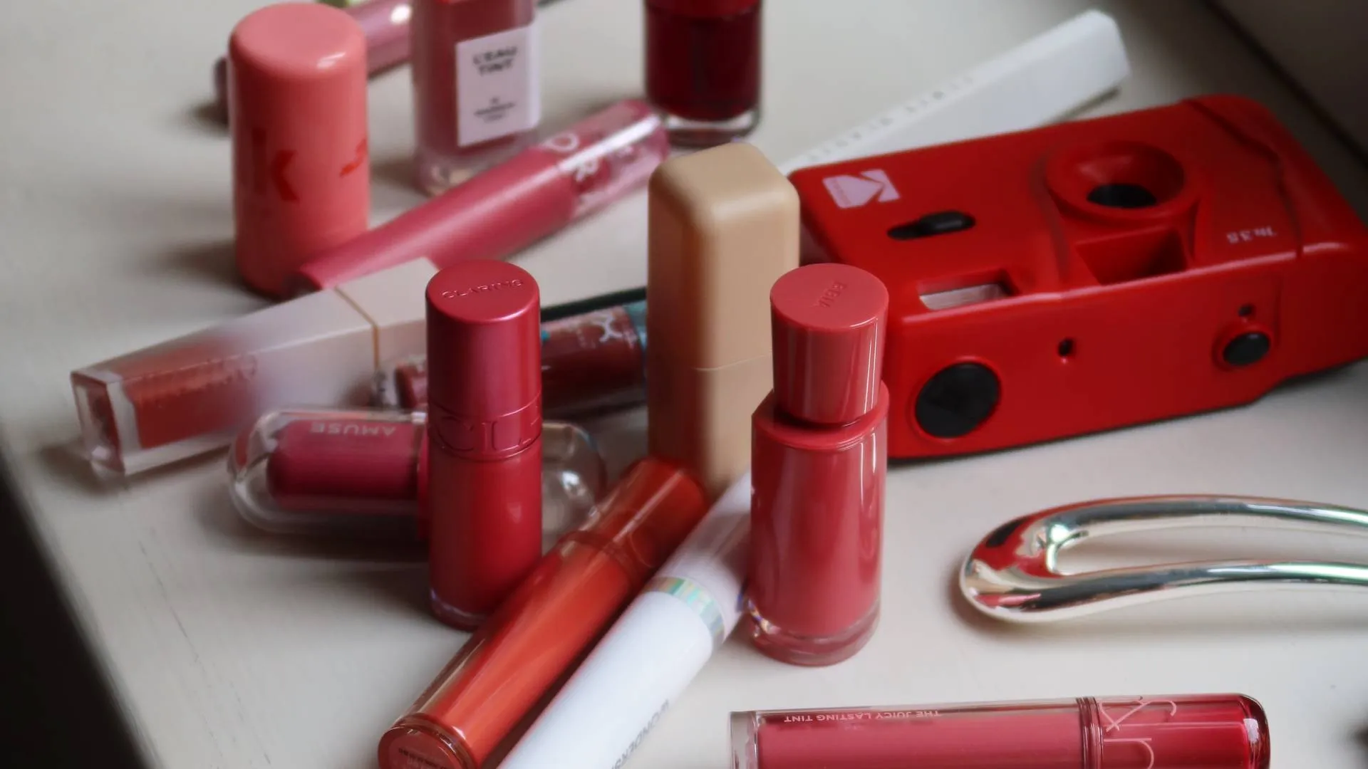 Flera olika lip tints i olika färger och förpackningar utspridda på ett bord.