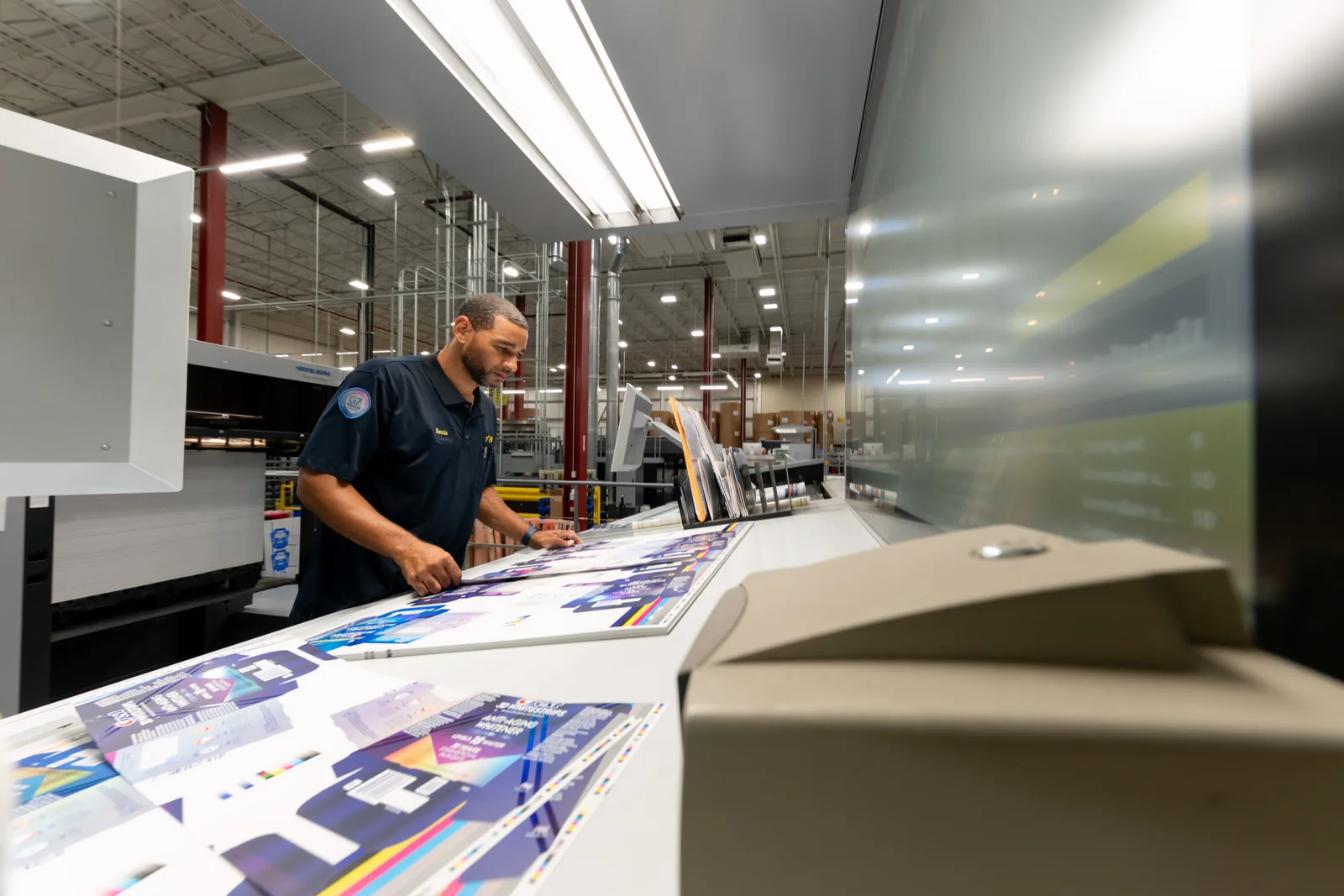 Employee reviewing printed packaging proof sheets on a press at Arkay's facility