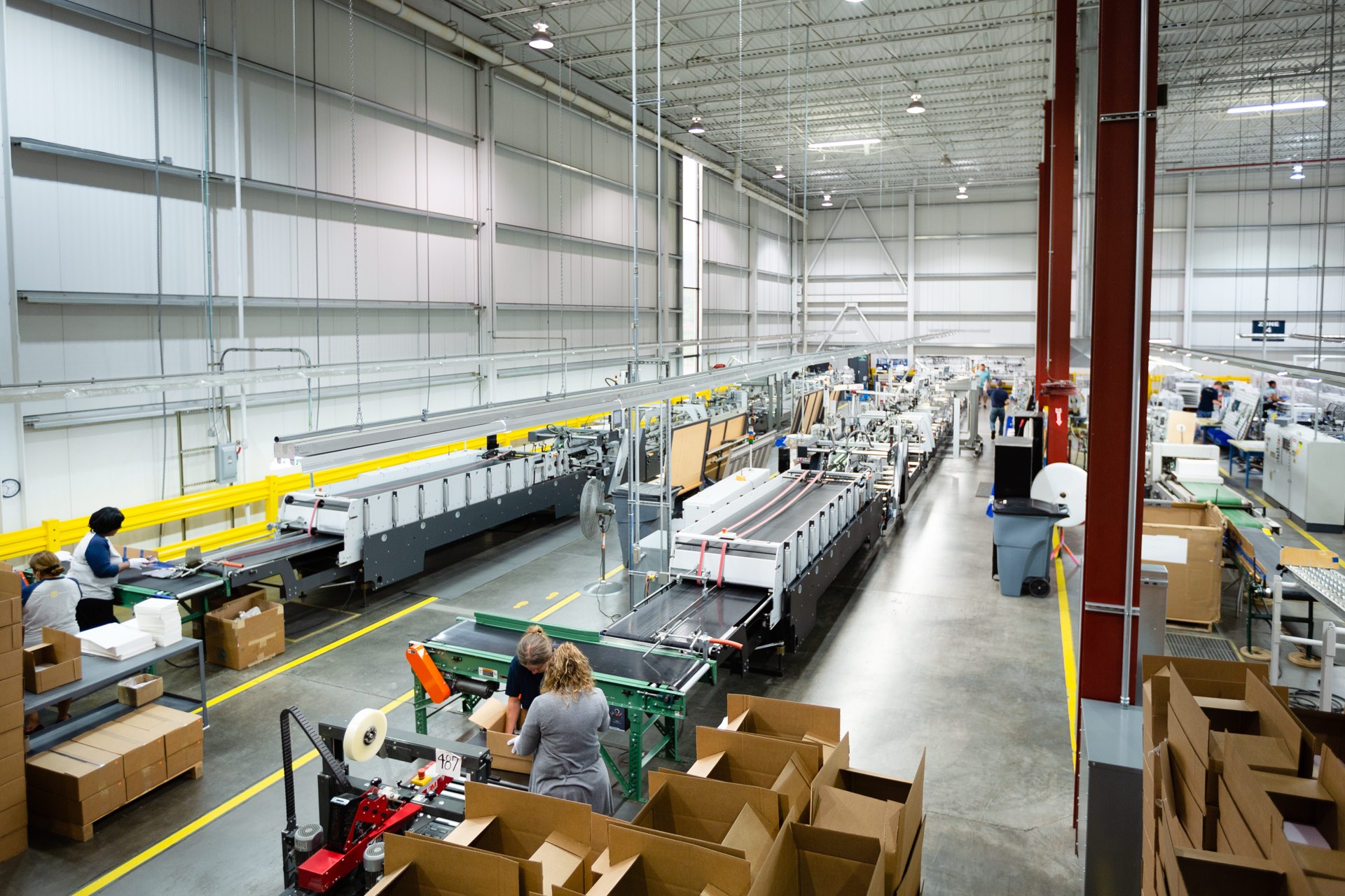 Finished folding cartons being hand-packed into shipping cases at the end of the folder-gluer lines, ready to ship to a fill site
