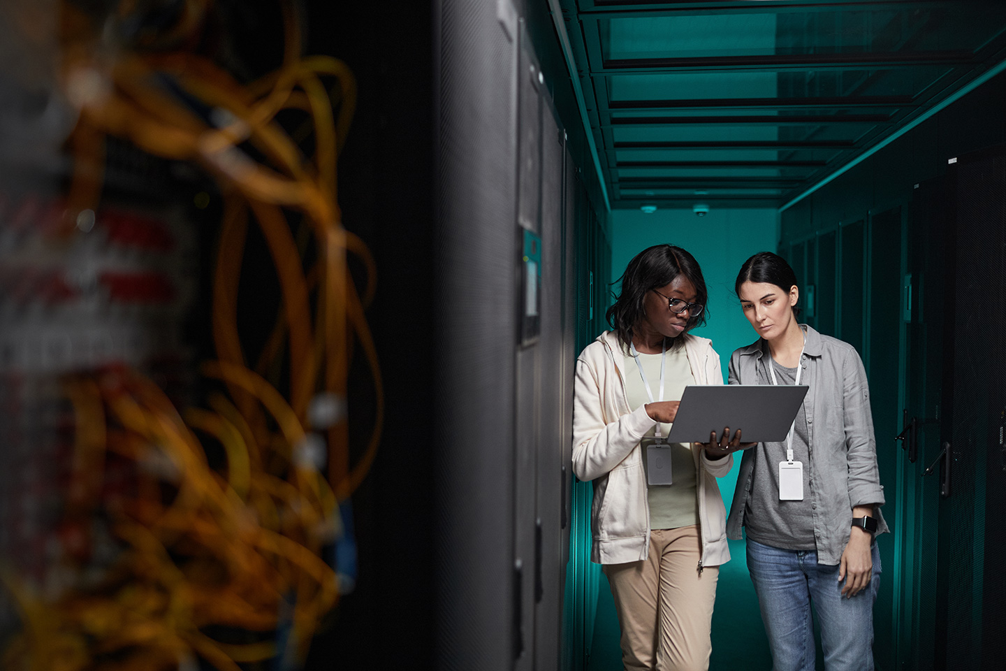Two enterprise IT technicians reviewing a laptop in a server room, discussing TeamViewer alternatives for enterprise remote support
