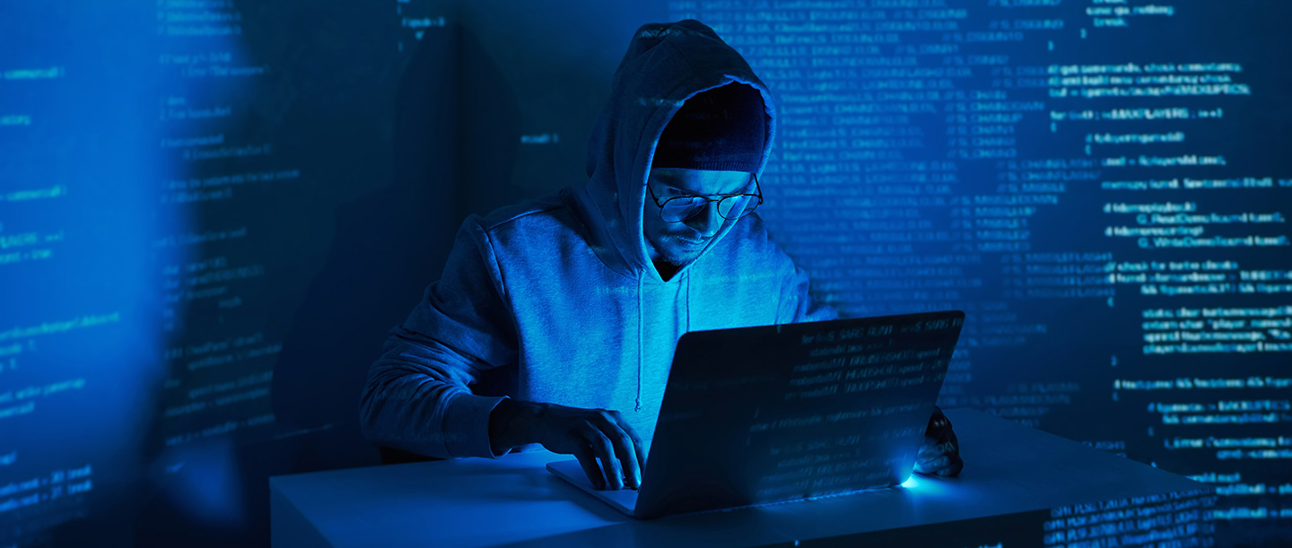 Man on a laptop in a dark blue environment, representing ransomware attack statistics
