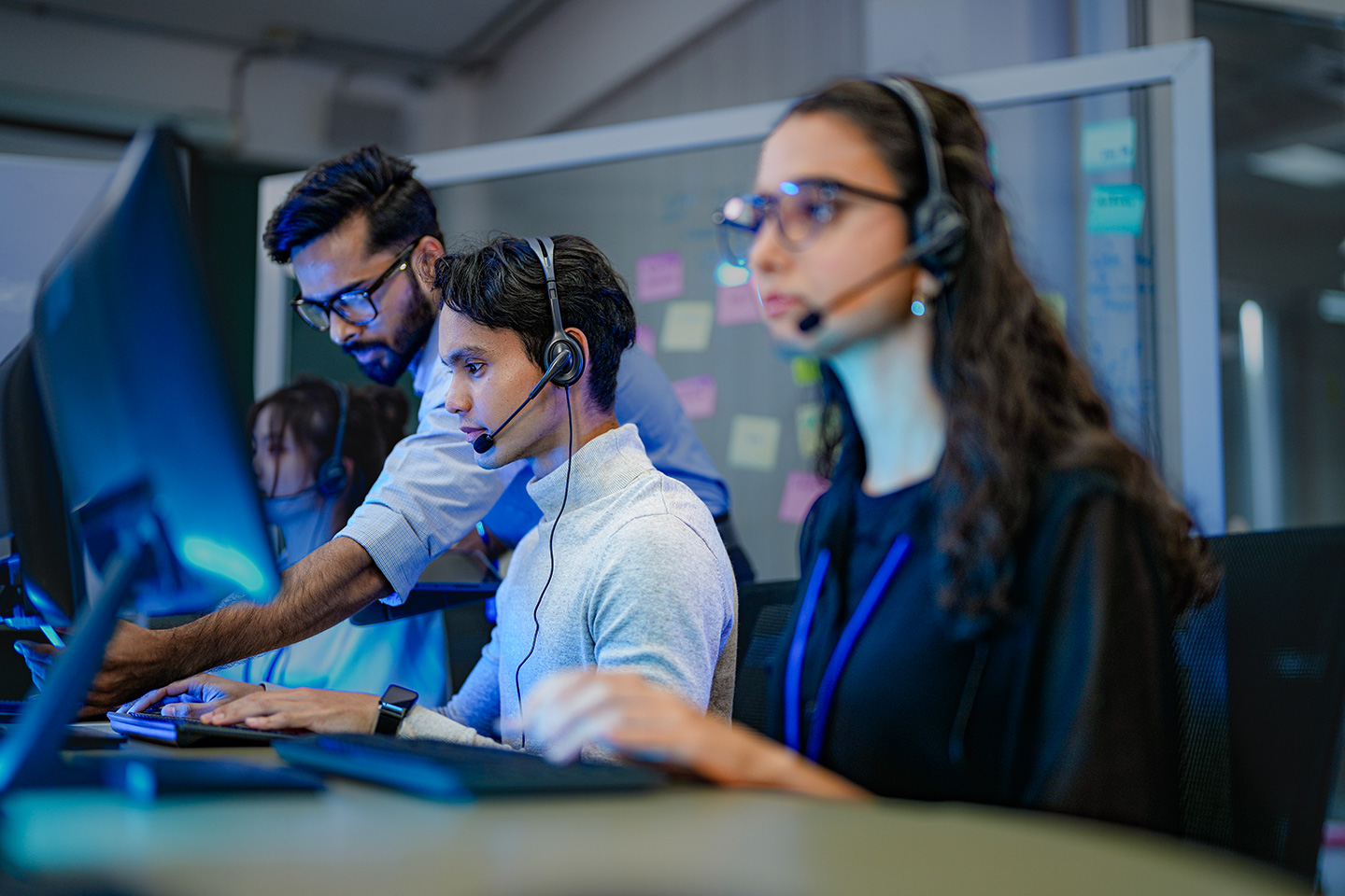 Technical support team members wearing headsets and working at computer stations in an agentic AI for technical support service desk