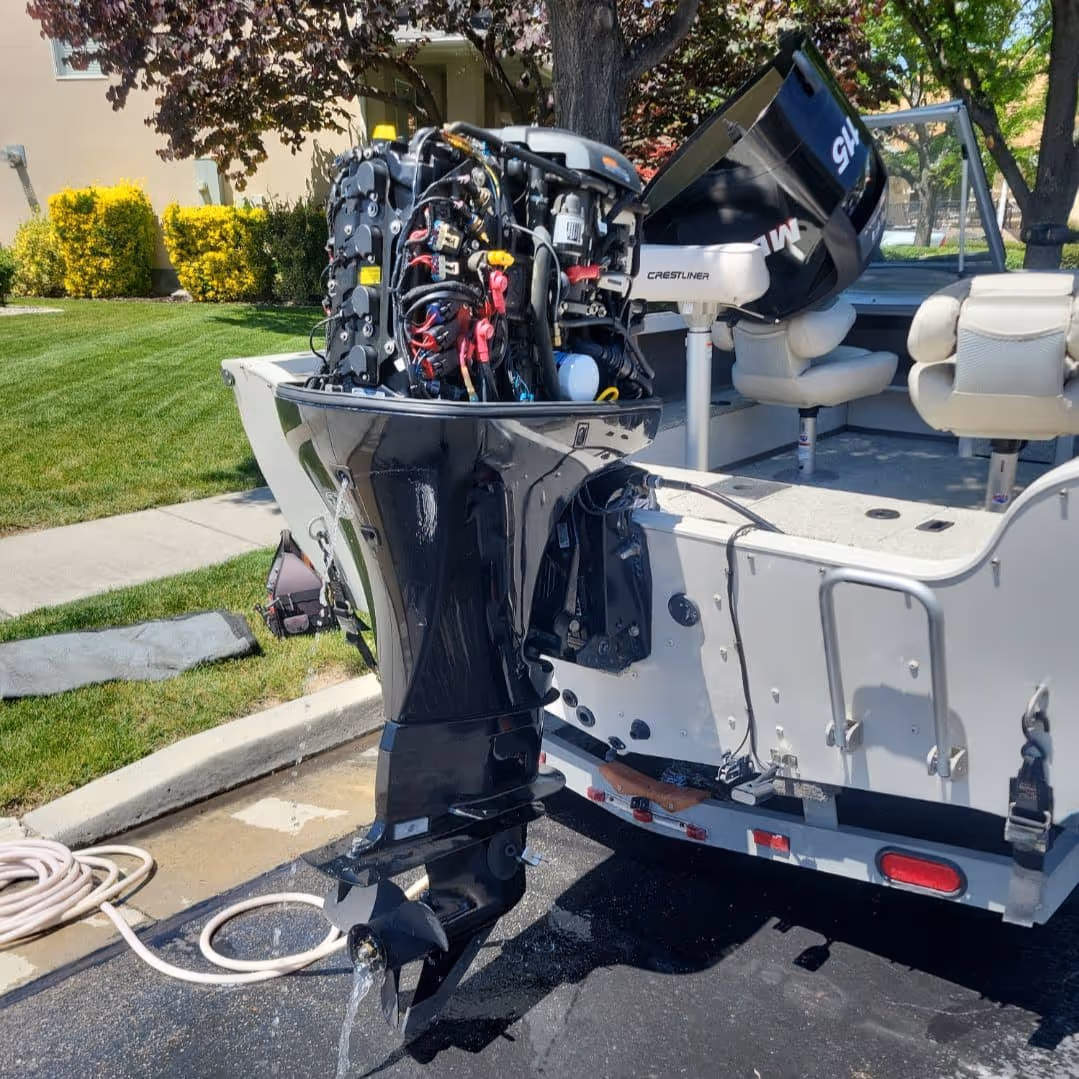 Boat engine undergoing an oil change during routine maintenance, with tools and equipment set up on a residential driveway.