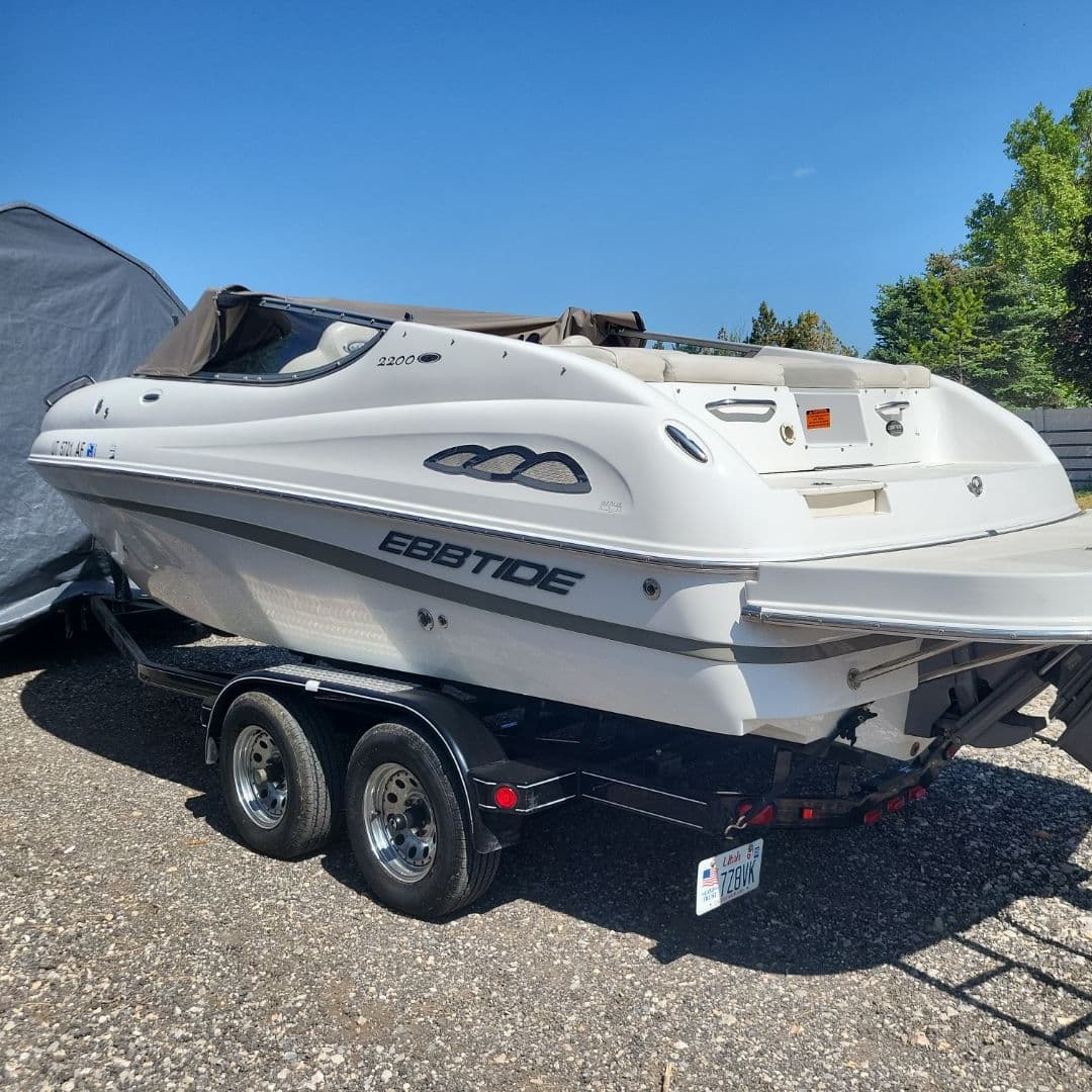 White speedboat on a trailer parked outdoors under clear blue sky, illustrating boat maintenance tips.