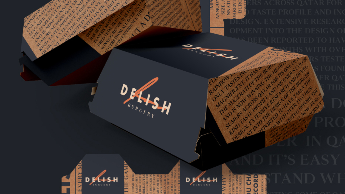 A pair of Delish Burger-branded burger boxes with text patterns and a logo on a dark background. The boxes are partially open, revealing a glimpse of the contents inside.