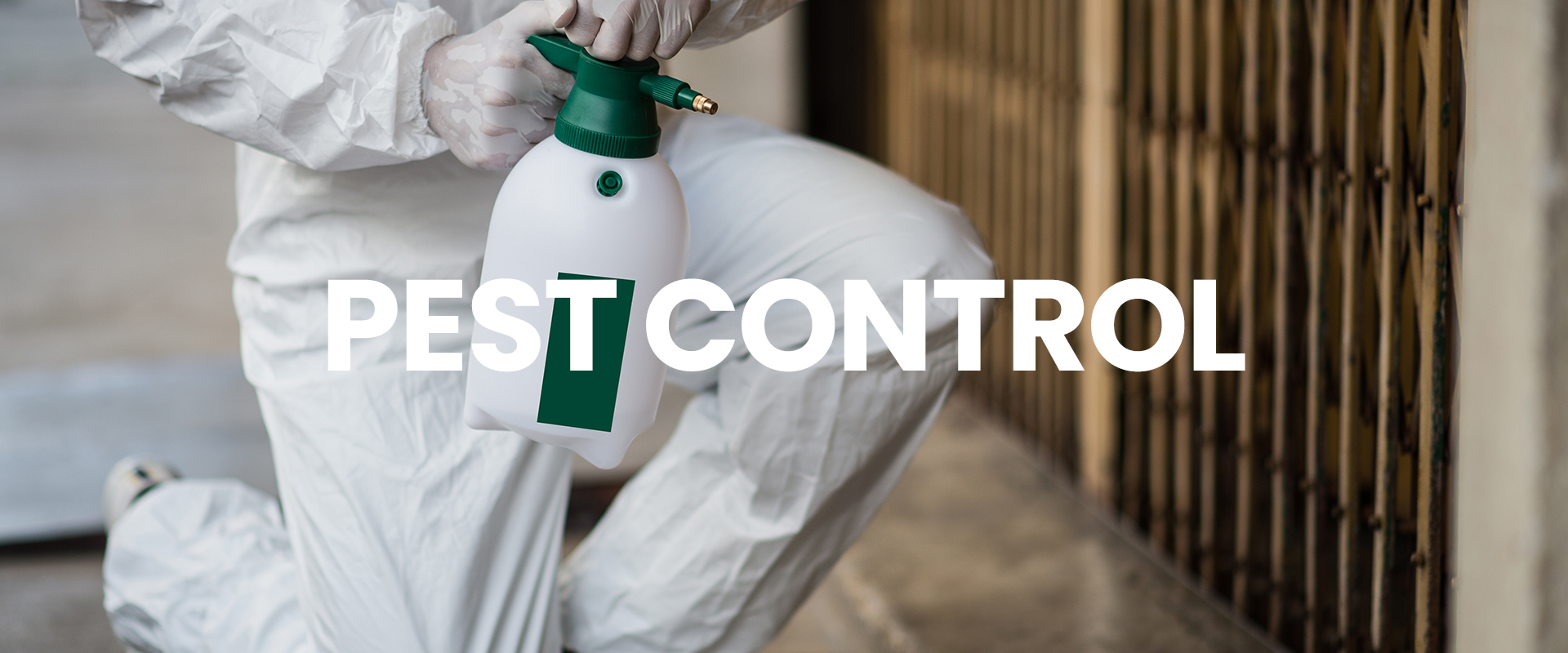 A pest control specialist kneeling by a wall to apply pesticides from a canister.