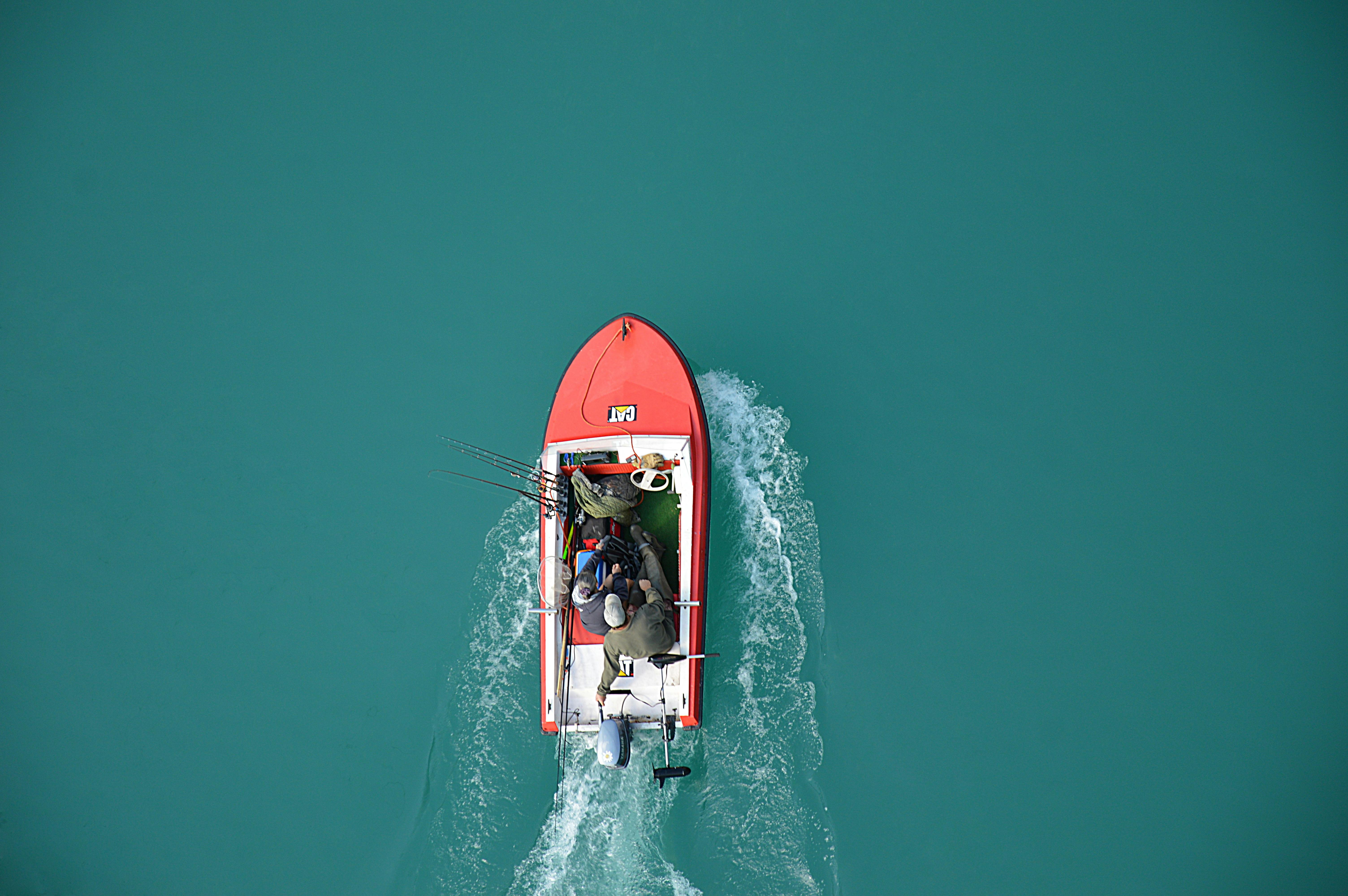 Top view of orange motorboat going through deep aqua water.