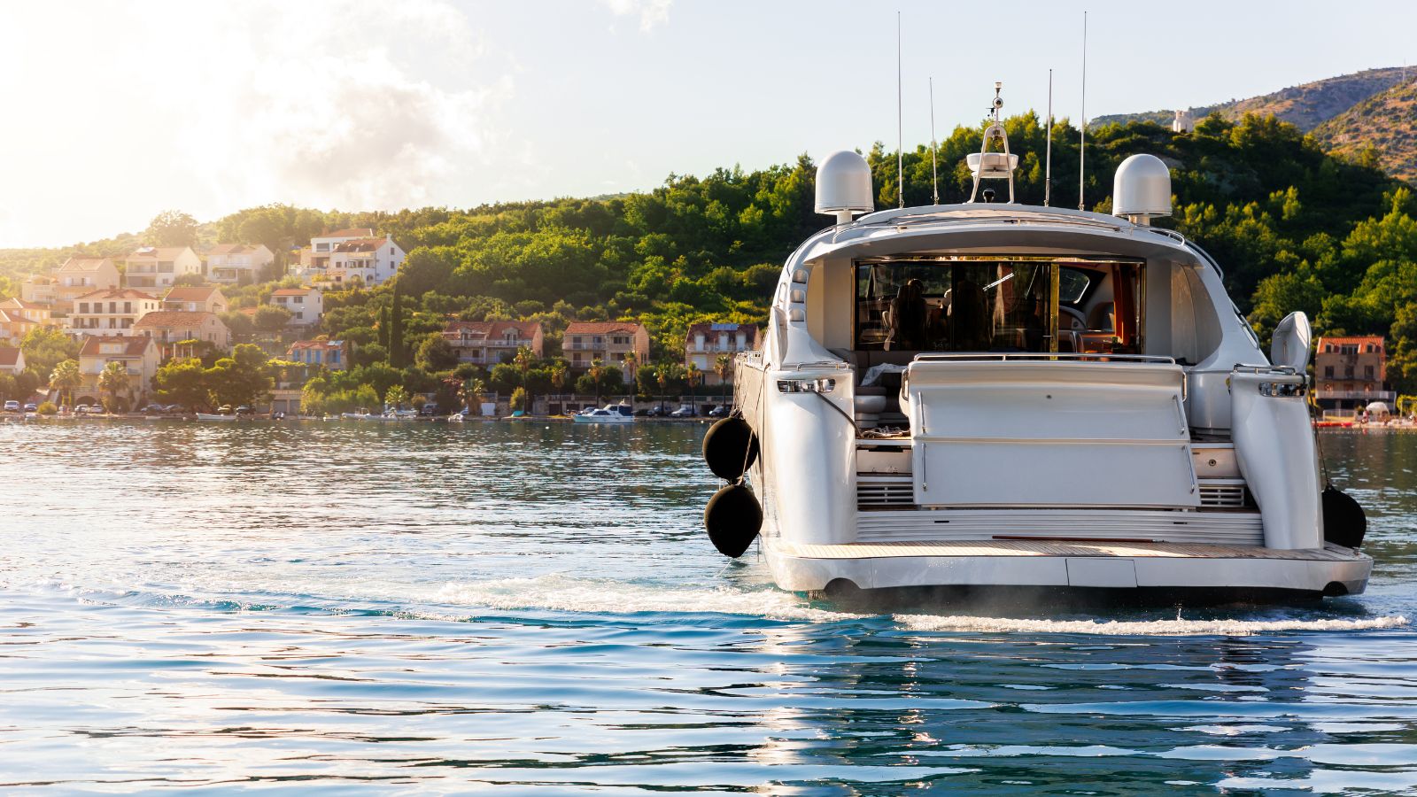45 foot motor yacht idling along a green and hilly coastline.