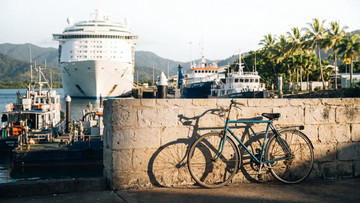 A tropical working wharf with a cruise ship berthed beside marine service vessels.