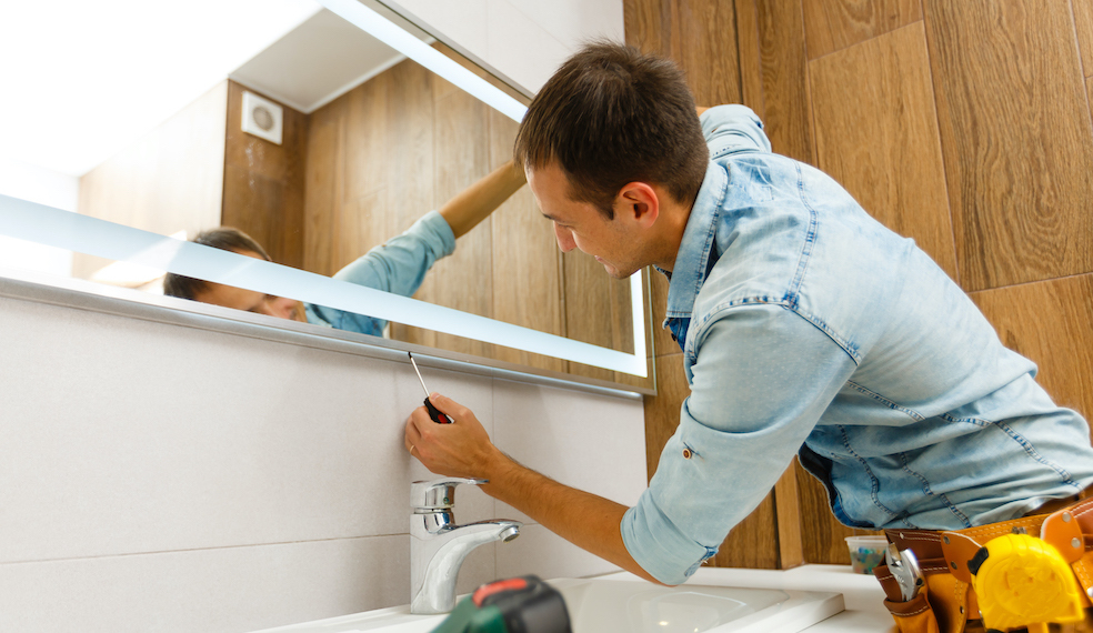 man installing modern mirror with lights