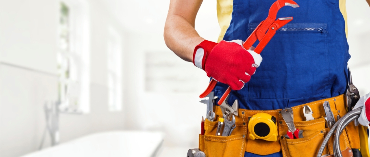 New Zealand home during a small water leak emergency, with a bucket under the dripping ceiling and emergency repair professional assessing damage.