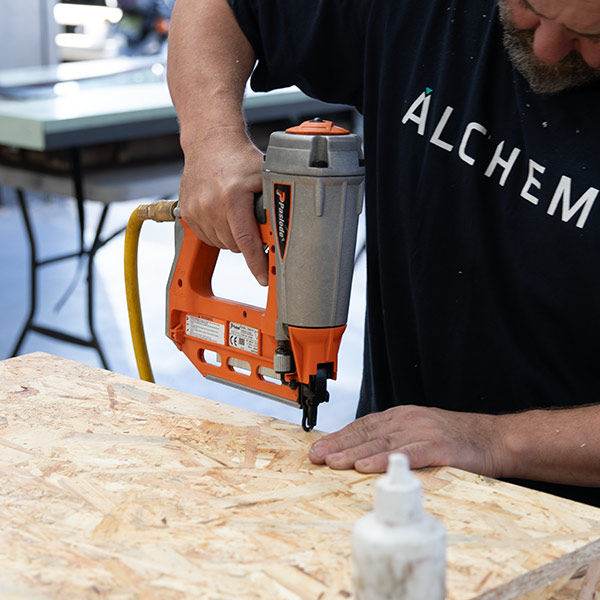 worker wearing alchemy tee shirt using a nail gun in the factory