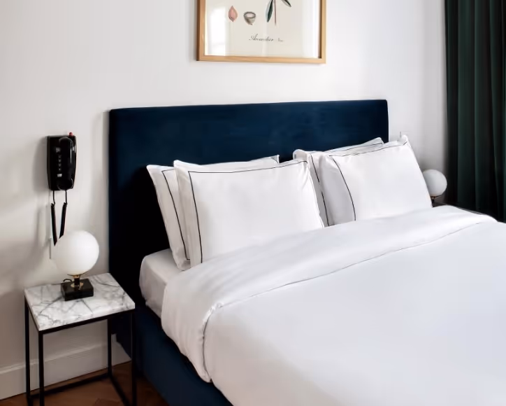 Chambre supérieure de l’hôtel Rendez-Vous Batignolles avec literie blanche et décor minimaliste