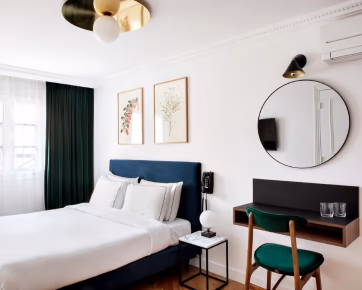 Chambre supérieure de l’hôtel Rendez-Vous Batignolles avec lit double, miroir rond et décoration élégante