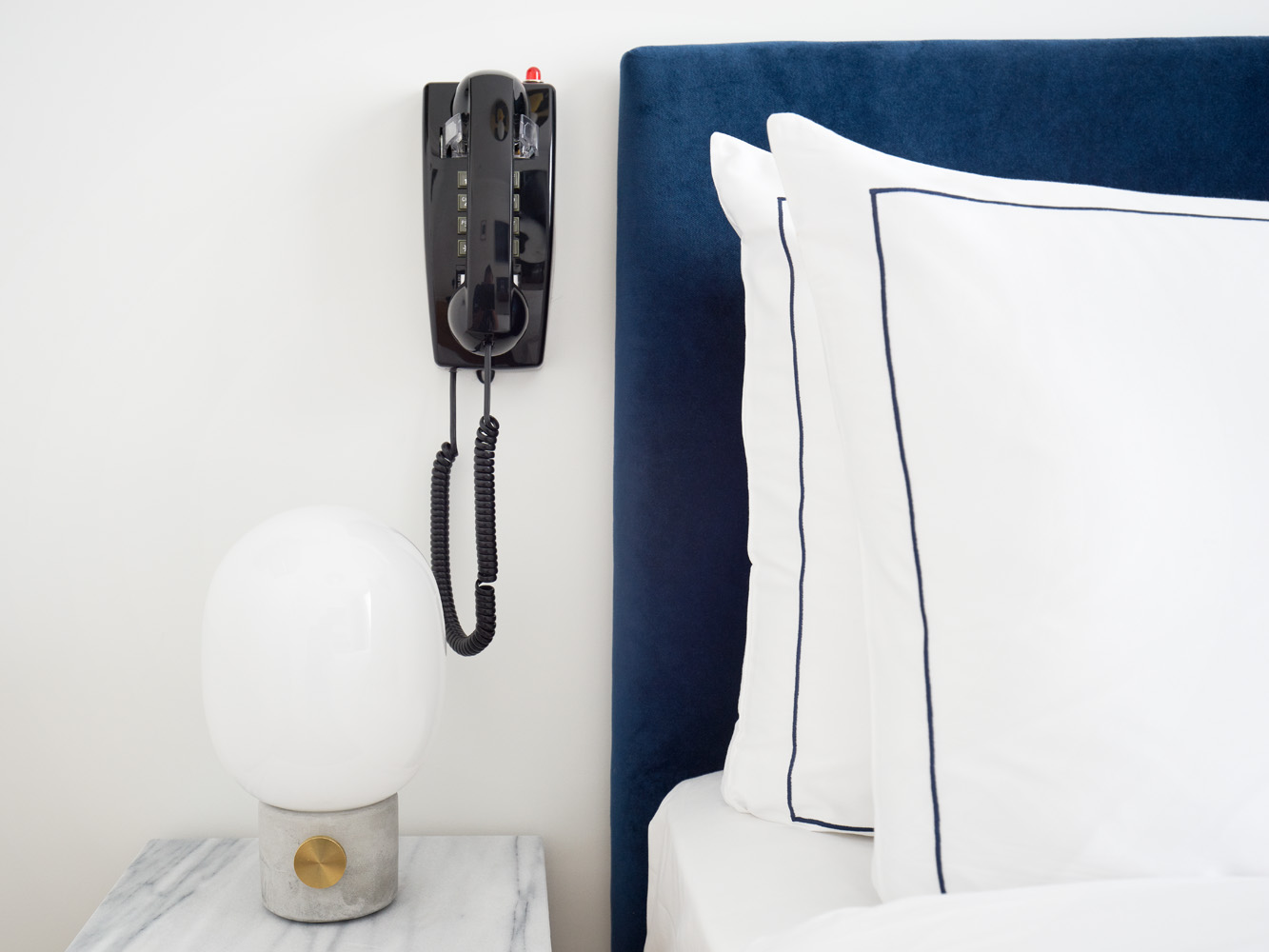 Détail de la chambre de l’hôtel Rendez-Vous Batignolles avec téléphone mural et literie