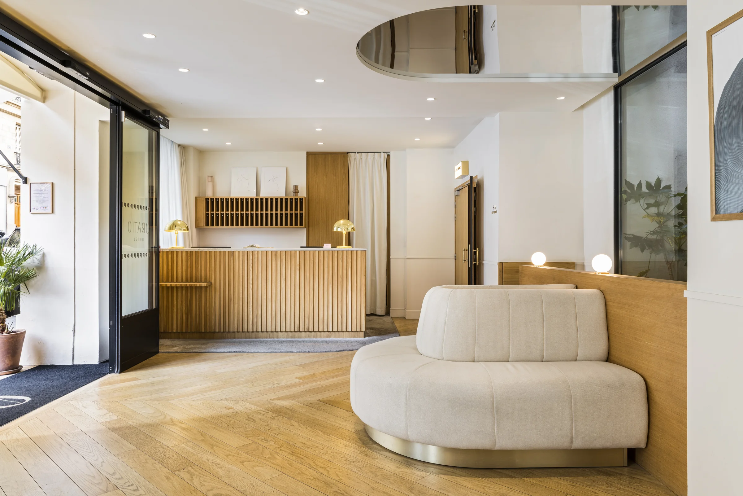 Vue de la réception de l'Hôtel Oratio avec son comptoir en chêne et canapé arrondi