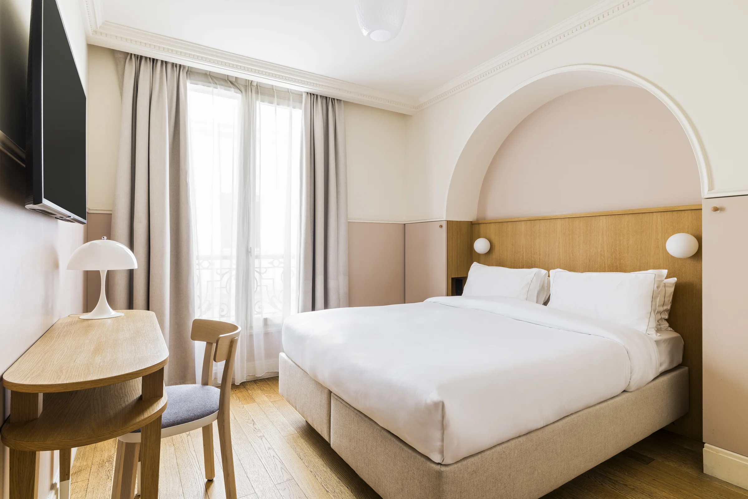Chambre Confort de l'Hôtel Oratio avec arche rose poudré, lit double et fenêtre sur Paris