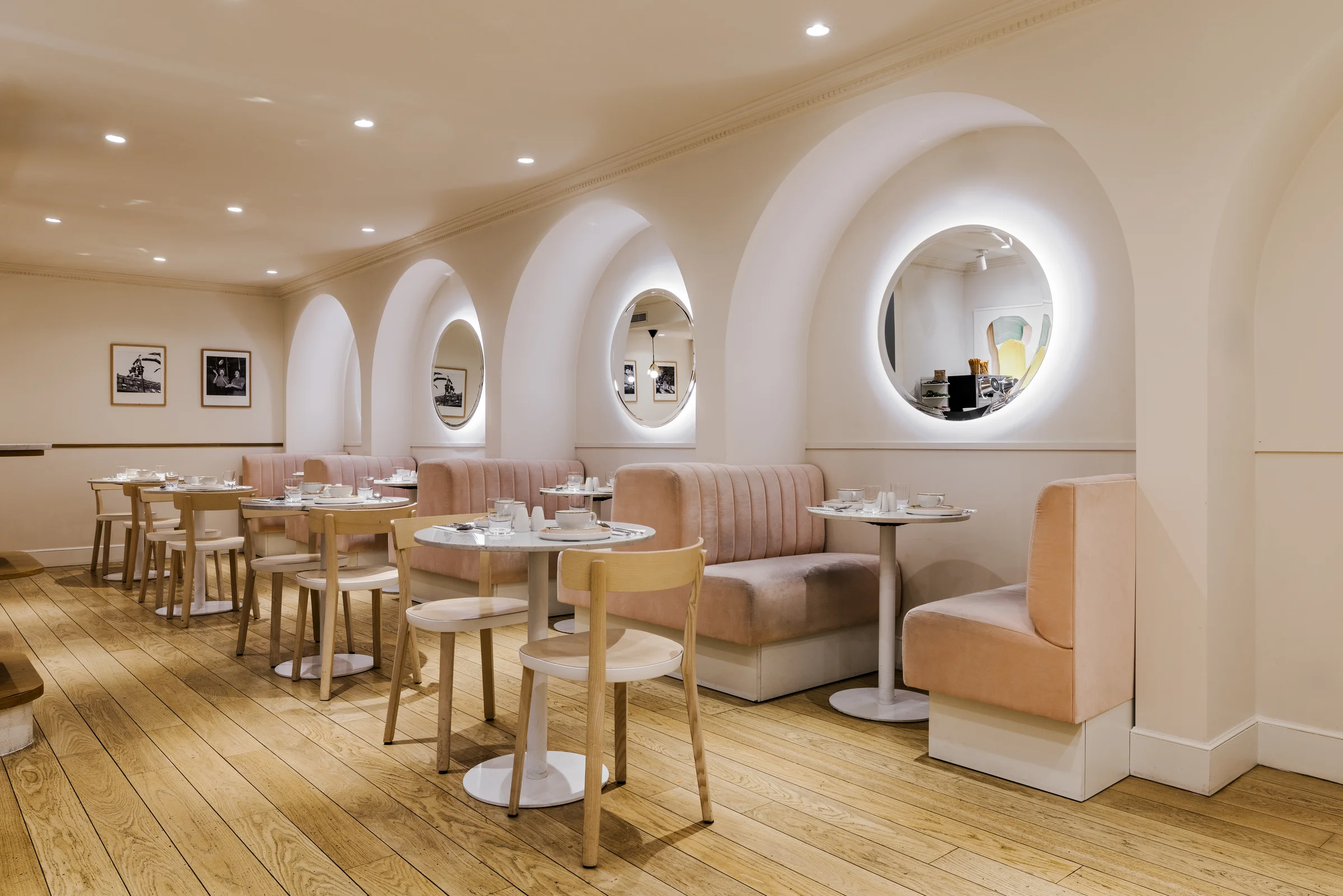Salle de petit-déjeuner de l'Hôtel Oratio, enfilade d'arches avec miroirs ronds rétroéclairés et banquettes roses