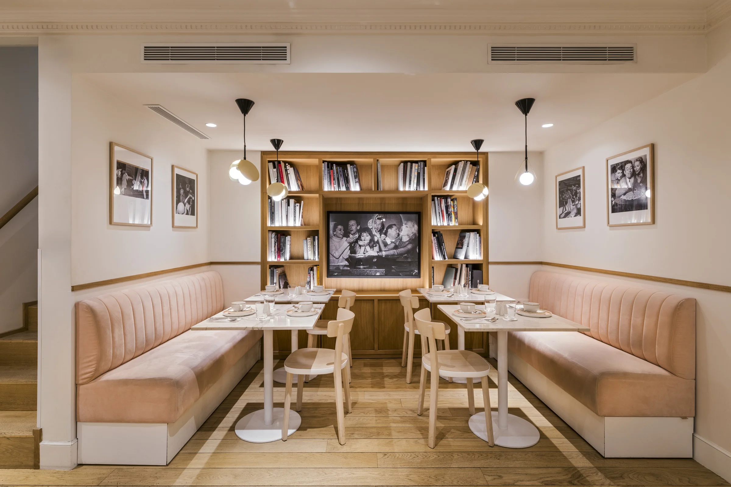 Salle du petit-déjeuner de l'Hôtel Oratio, grandes banquettes roses et bibliothèque centrale