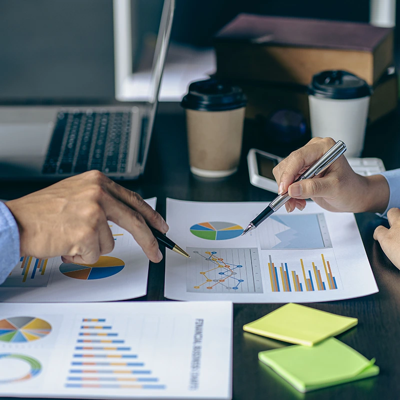 Close-up of two professionals reviewing financial charts and graphs during financial structuring and cost control management planning