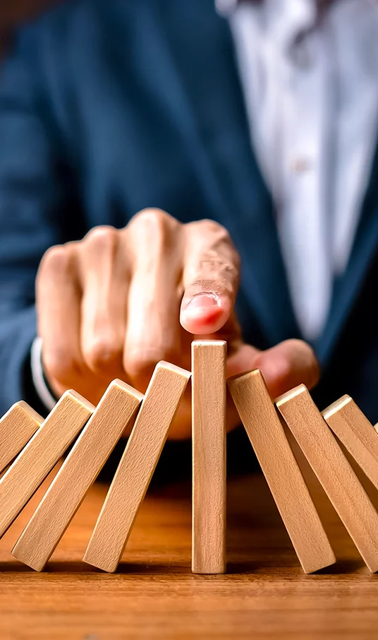 Representation of strategic asset recovery with a hand stabilising falling dominoes, symbolising Merifund Capital Management’s expertise in capitalising on distressed securities to enhance portfolio value.