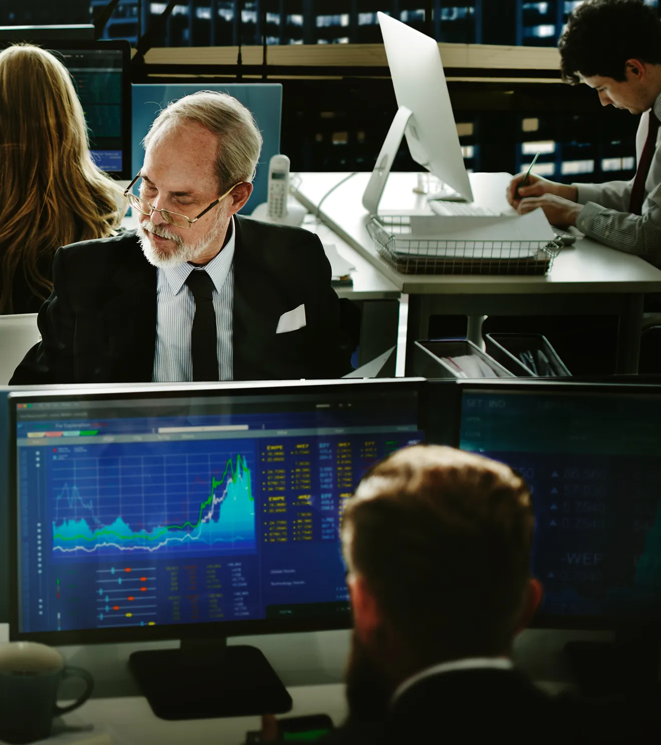 Financial analysts working diligently in the Merifund Capital Management HQ office, monitoring investment performance on multiple screens, reflecting a precise and sophisticated approach to investment management.