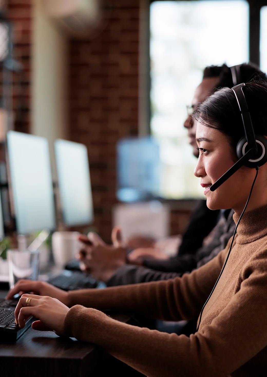 Friendly customer support representative wearing a headset, assisting clients in an office environment.