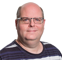 Middle-aged bald man wearing glasses and a dark striped shirt, smiling slightly.