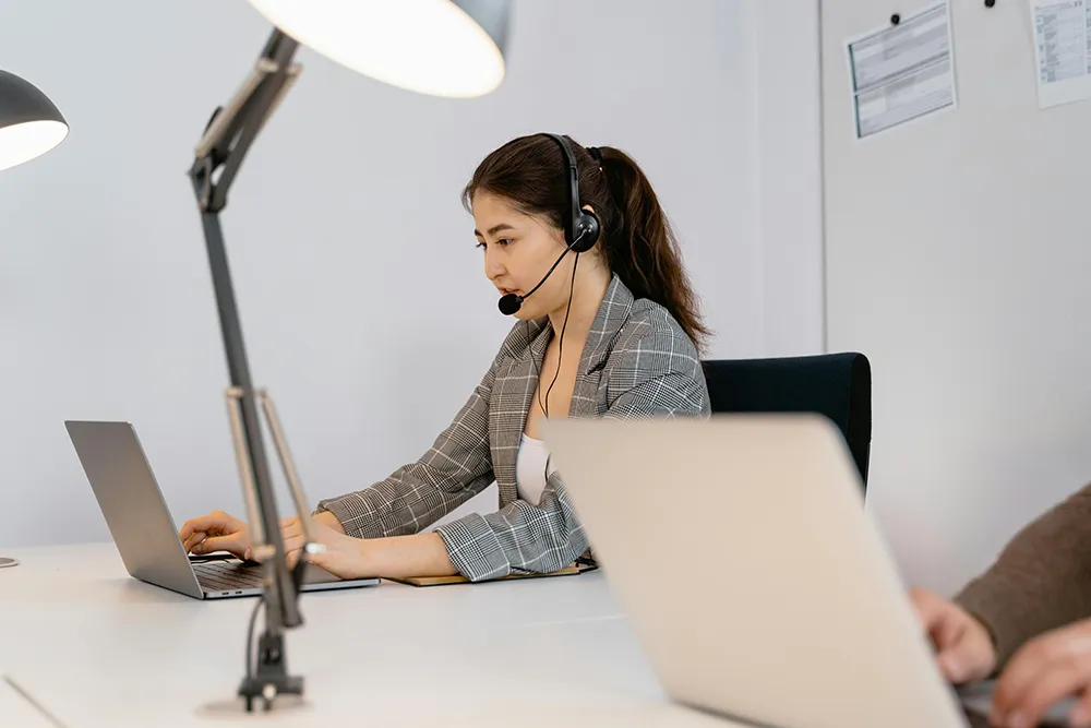 Image of a woman behind a pc, offering support.