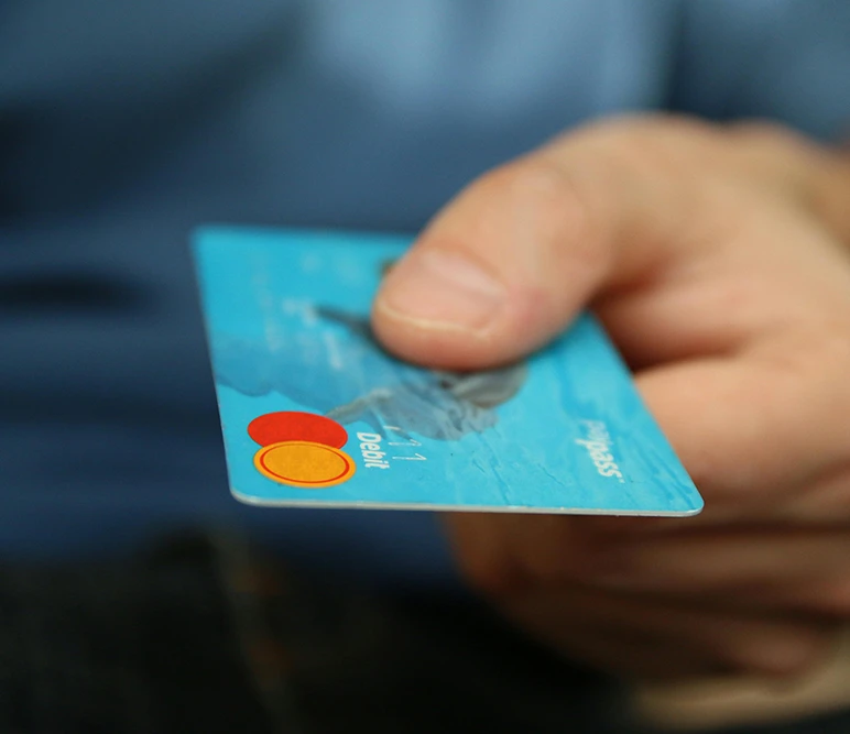 Image zoomed in on a mans hand, holding a mastercard.