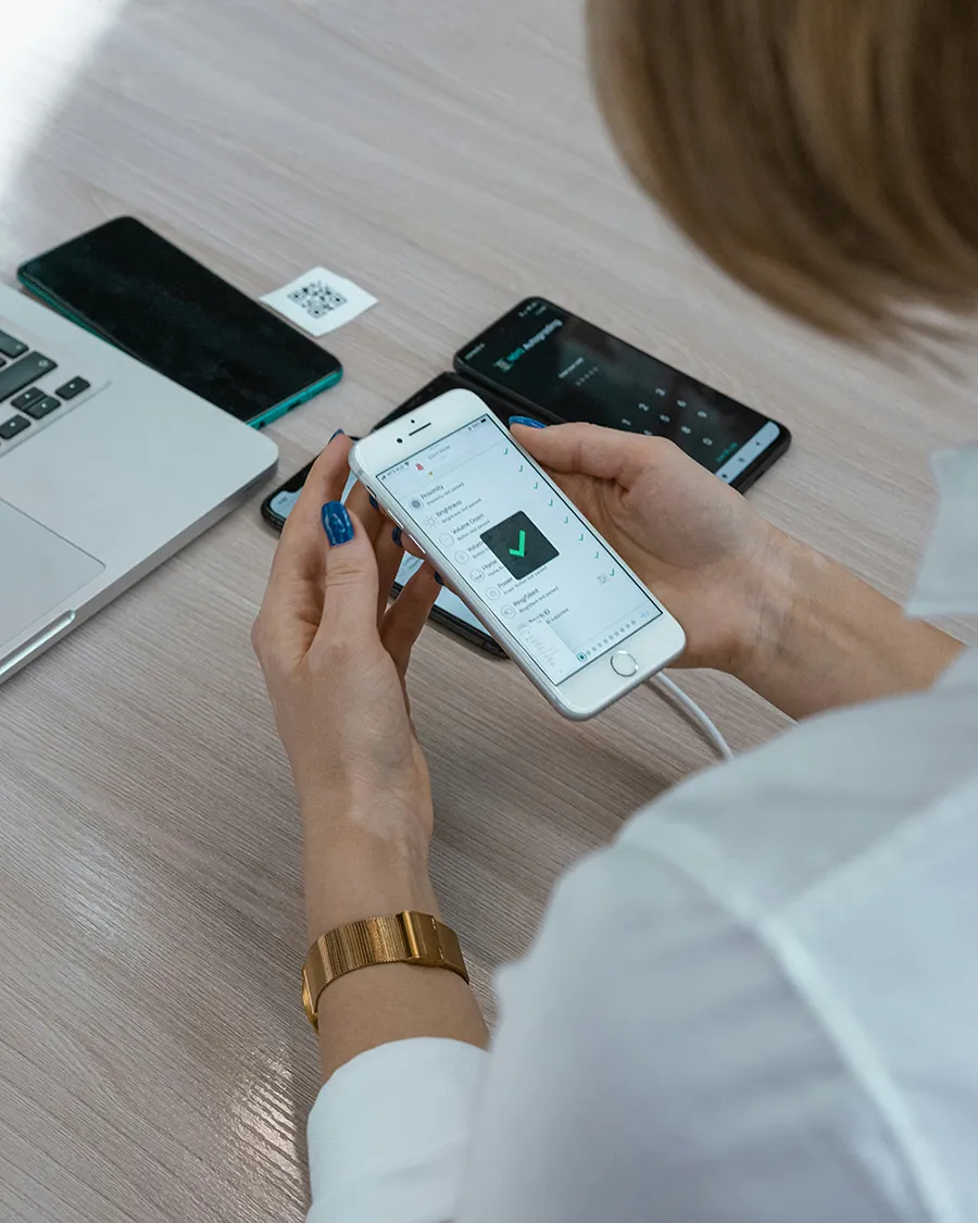 Woman holding a phone with a checkmark on the screen.