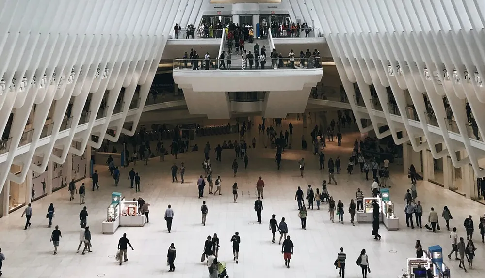People in a trainstaton, photo taken form higer up, zoomed out.
