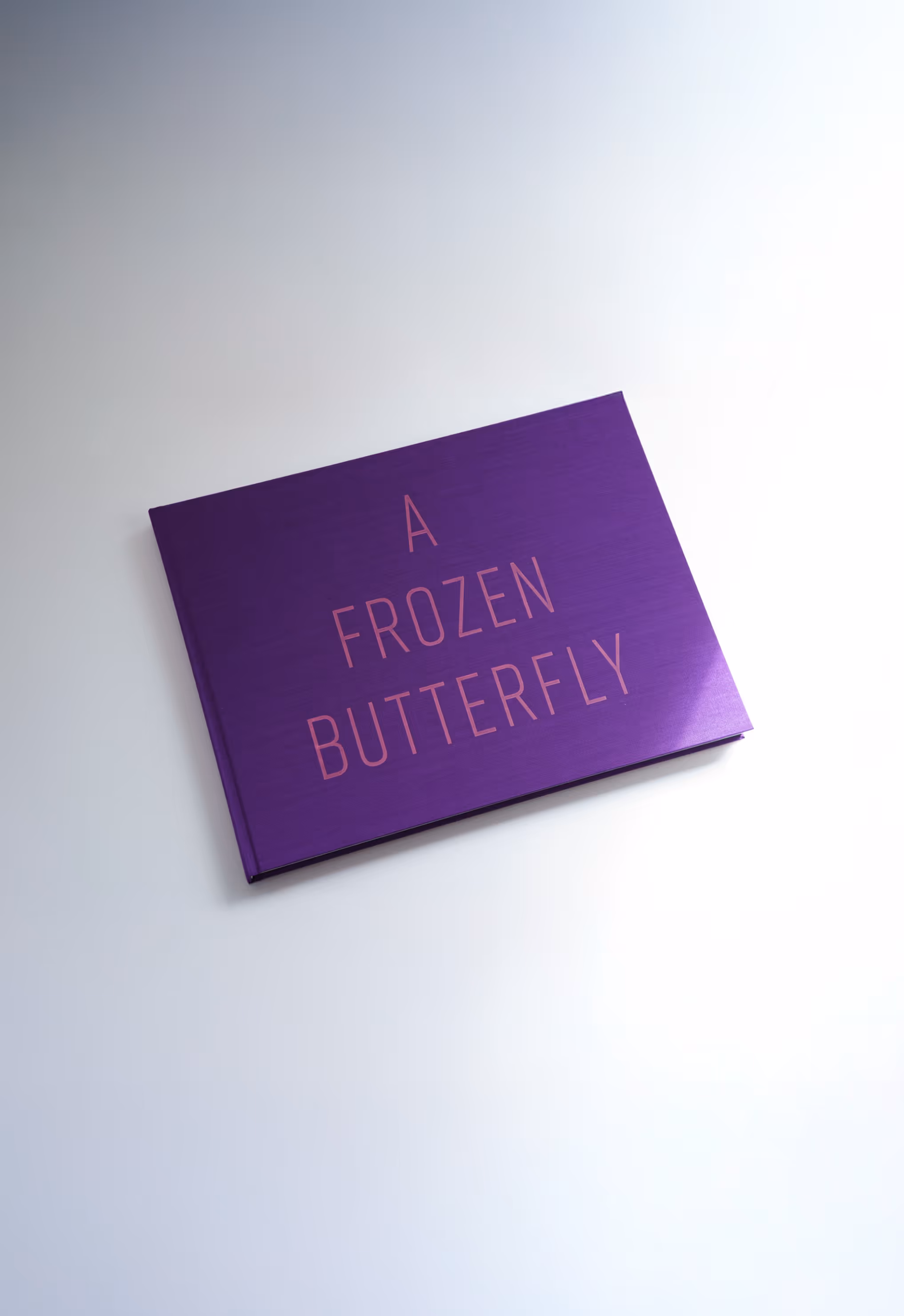Purple hardcover book titled 'A Frozen Butterfly' on a white surface.