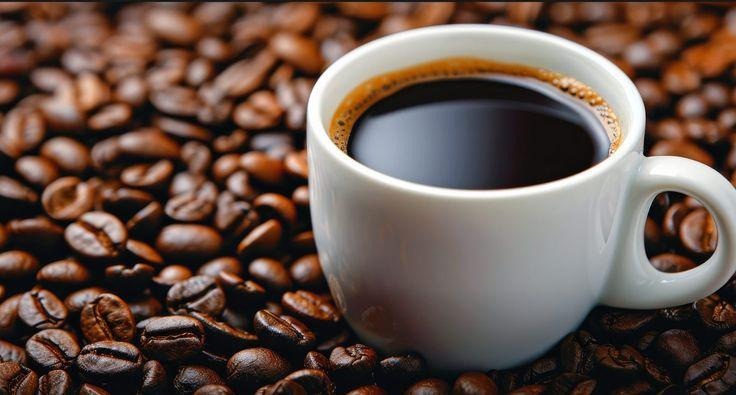 This may contain: a cup of coffee sitting on top of a pile of coffee beans