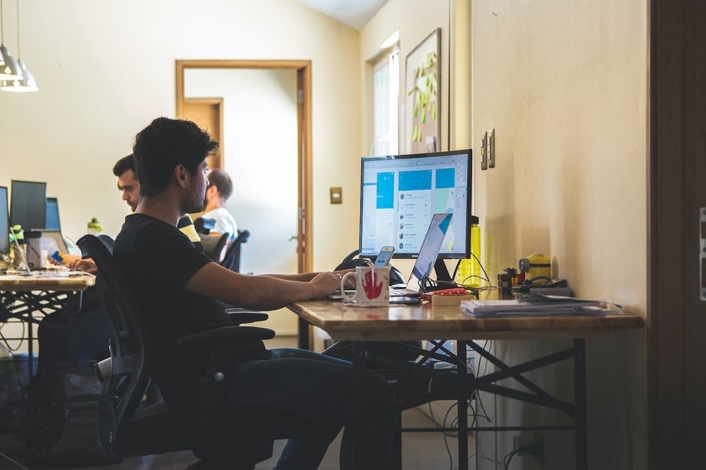 Office environment with team members working at computers, using workflow approval software to manage tasks, streamline processes, and enhance productivity, illustrating a modern workspace with collaborative software tools.
