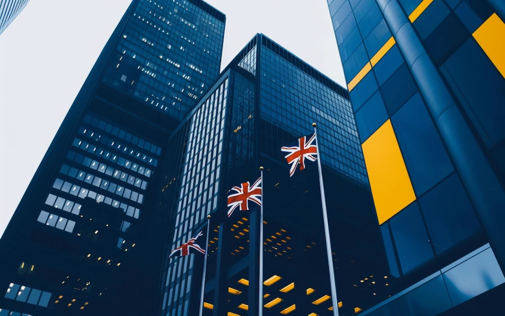 UK financial district with modern skyscrapers and British flags, symbolizing the impact of EMIR Refit regulations on the derivatives market and the adoption of ISO 20022 XML format for improved reporting transparency.