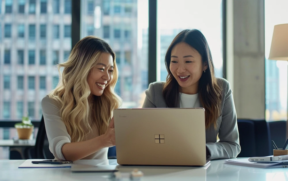 Two professional women in a modern office collaborating on a laptop, discussing finance automation solutions. The environment is bright and modern, reflecting productivity and innovation in financial processes.