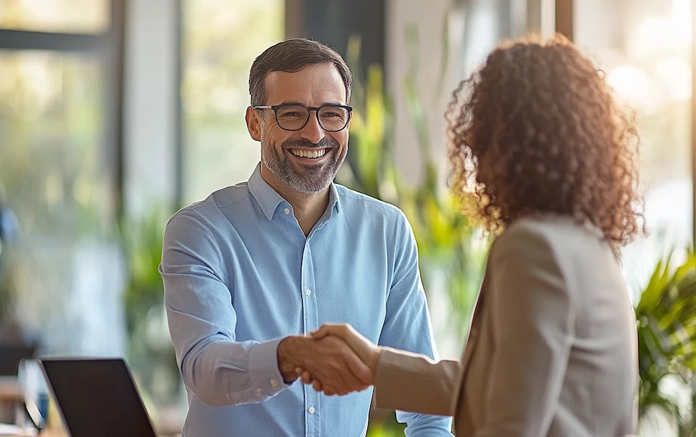 Business professionals shaking hands in a modern office, symbolizing successful rebate agreements. Learn about different types of rebates and how they benefit businesses in our latest blog.